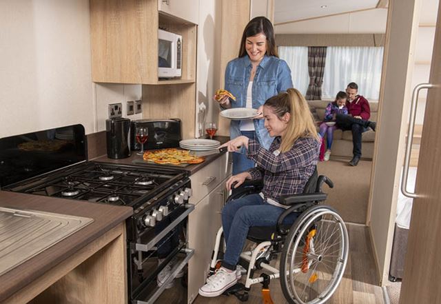 A woman cooking dinner in a wheelchair accessible caravan kitchen