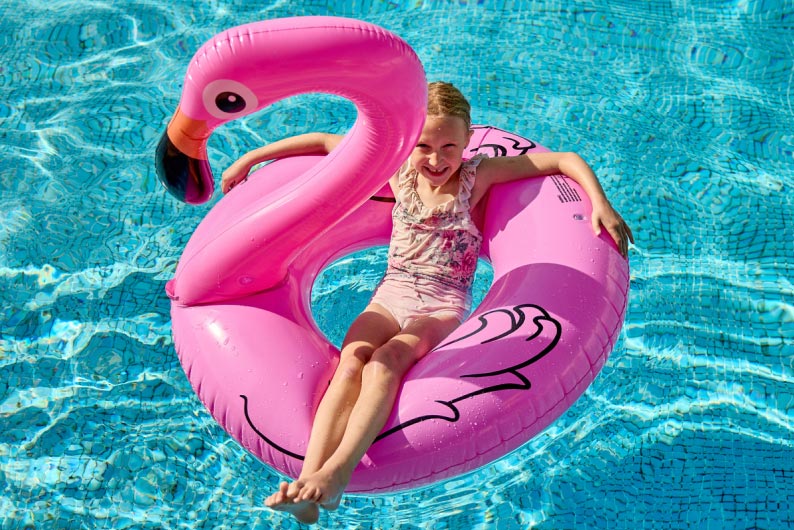 Little girl laying in pink inflatable flamingo 