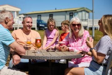 Family sat at picnic bench in the sunshine