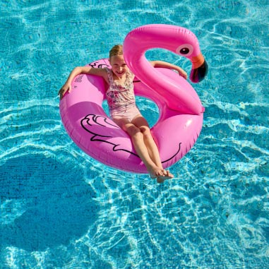 Girl laying in pink flamingo in pool