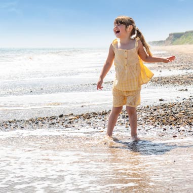 Little girl wearing yellow dress in the sea