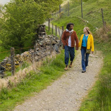Man and woman holding hands walking through the woods