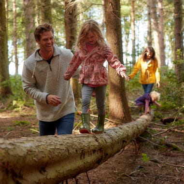 Little girl walking along tree trunk in woods