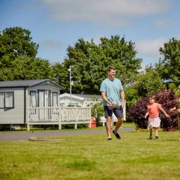 A father with his child walking past a row of holiday caravans