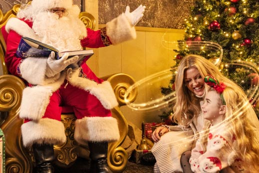 Little girl sat on mums lap listening to Father Christmas read a story
