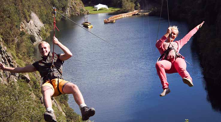 two people sliding down a zip wire through a quarry