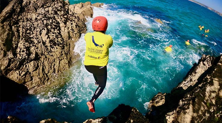 A person jumping into the sea coasteering in Cornwall