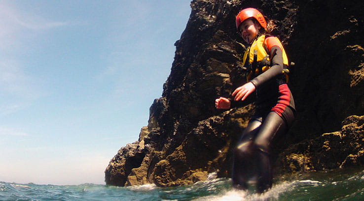 girl jumping into the sea from a rocky cliff