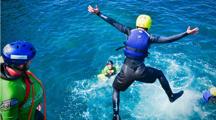 people jumping off  a cliff into the sea