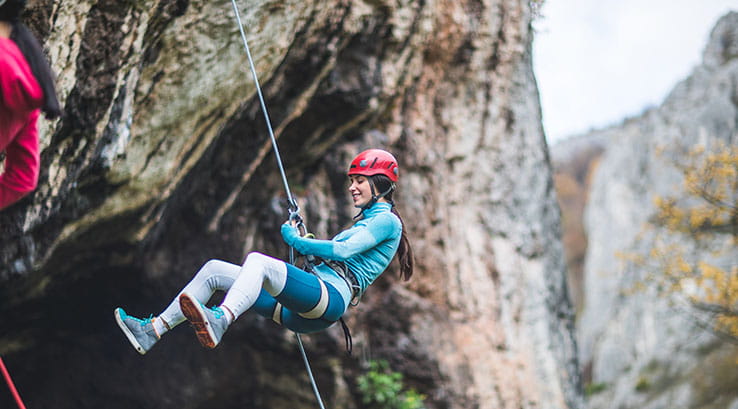 A woman abseiling down a cliff face