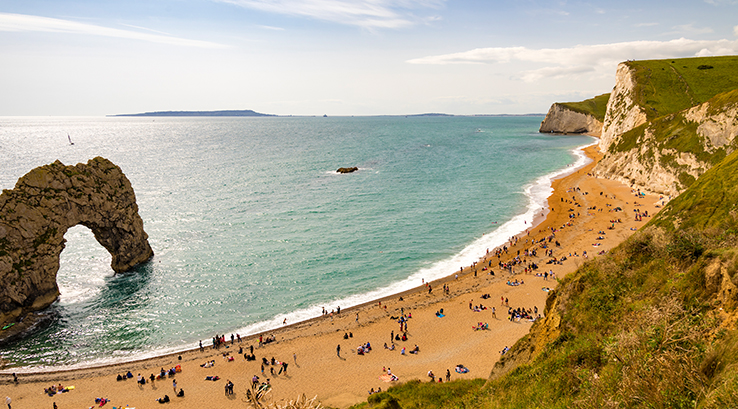 durdle door rock formation and beach on a hot, sunny day