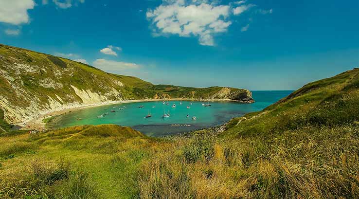 view of lulworth cove from behind the beach on a sunny day