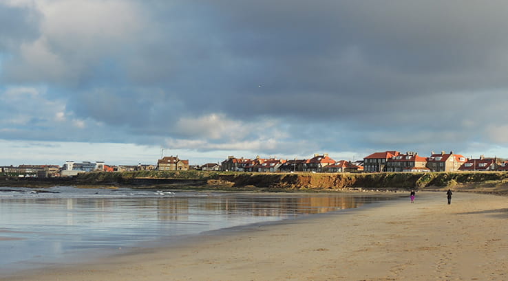 A view across the sand of Seahouses Beach towards the town