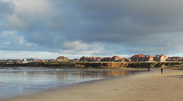 A view across the sand of Seahouses Beach towards the town