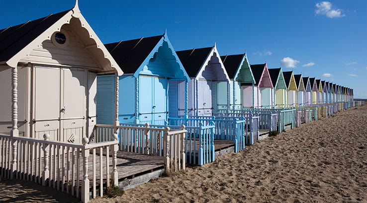 Colourful beach huts lining the sand at West Mersea Beach, Essex