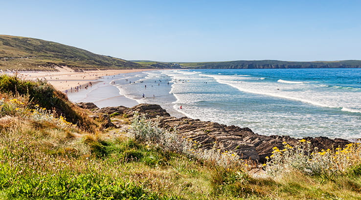 Clifftop view of waves rolling in to Woolacombe beach on sunny day