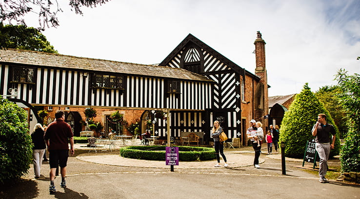 People walking around outside Samlesbury Hall on a sunny day