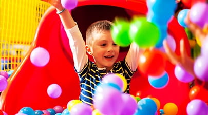 boy at bottom of a slide with balls
