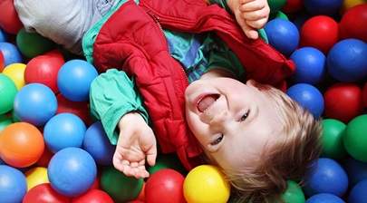 A child laughing whilst lying down in a ball pool