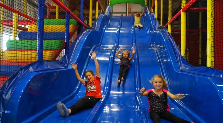children sliding down a large indoor slide