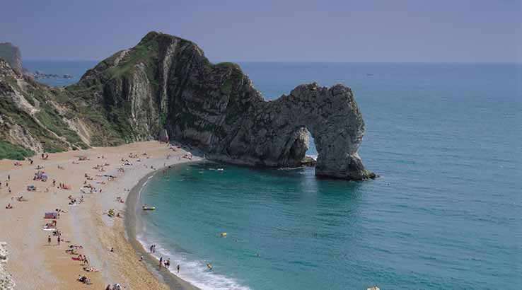 a view of durdle door beach and rock formation from the cliffs above