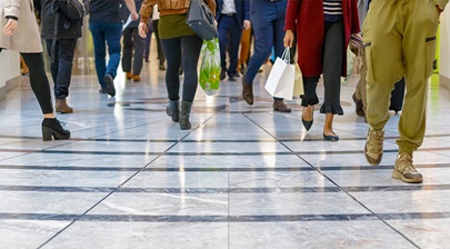 People's legs walking along a shopping centre with bags