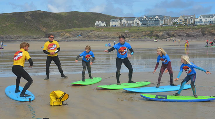 group of children being taught how to surf on the beach