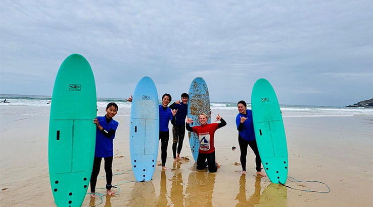 A group of people taking a surfing lesson at Holywell Bay in Cornwall