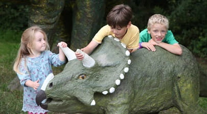 3 children with a model triceratops at Tenby Dinosaur Park