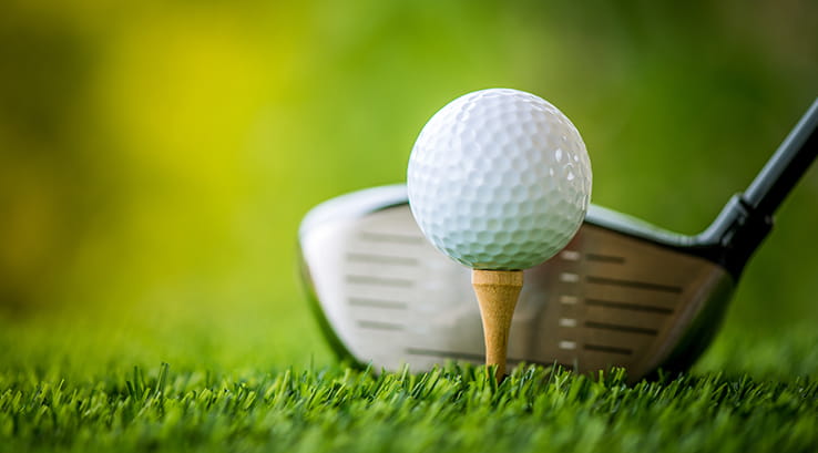 A close up image of a golf club and golf ball on its tee
