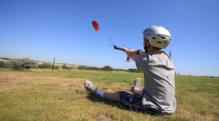 a boy sat on the ground flying a kite