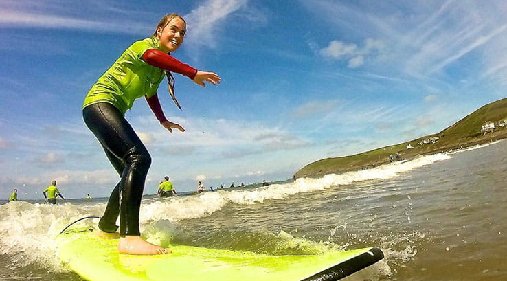 A woman catching a wave at Croyde Bay during a surfing lesson with Surf South West