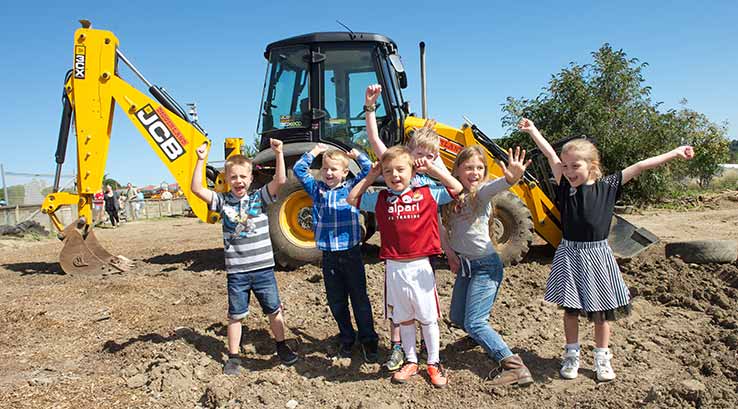 Children standing in front of a JCB digger at Diggerland, Durham