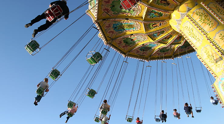 A view from below of people riding the giant swings at a fairground