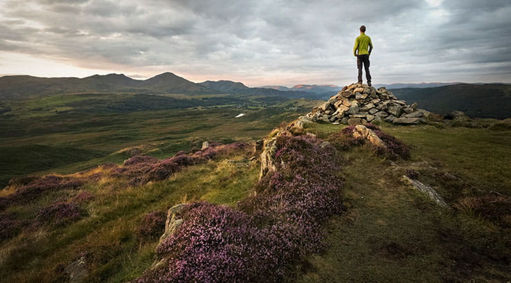 A man standing on the edge of a mountain enjoying the views of the Lake District