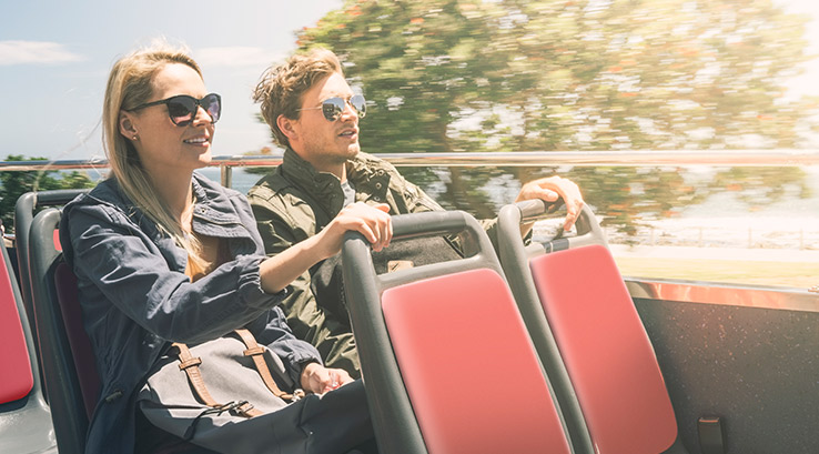A couple smiling on an open top bus
