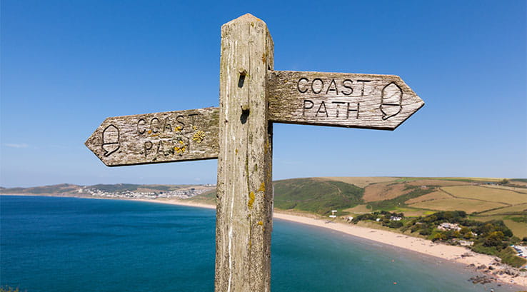 A sign for the coastal path overlooking a Devon beach