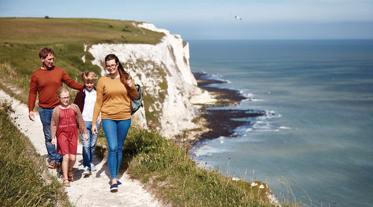 A family walking along the coastal path with the White Cliffs of Dover in the background