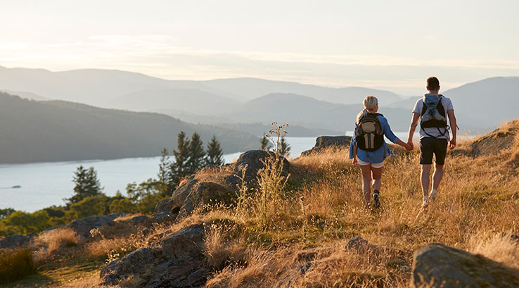 A couple walking along a grassy hill in the Lake District