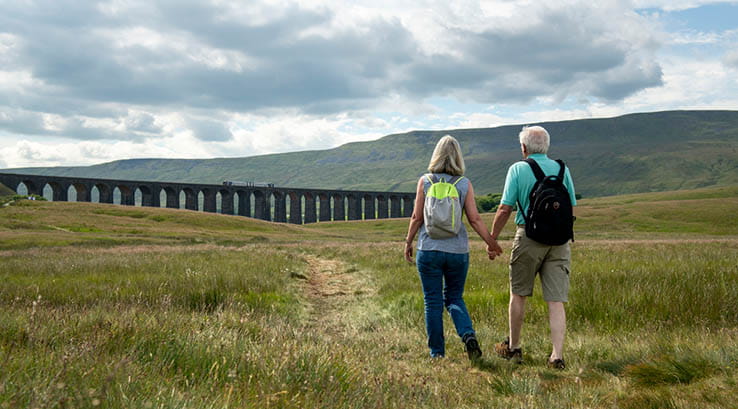 A couple walking towards the Ribblehead Viaduct