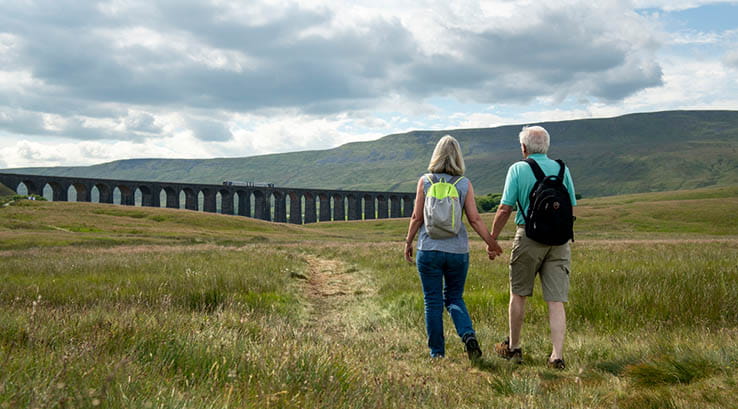 A couple walking towards the Ribblehead Viaduct
