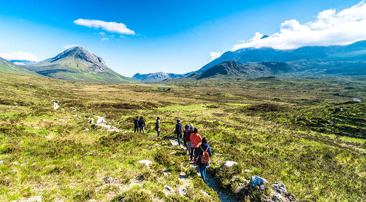 A group of hikers making their way over grassy hills in Scotland