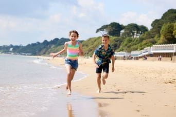 two children running along a sunny, sandy beach