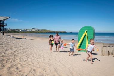 family running along sandy sunny beach