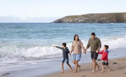 family walking along beach alongside sea