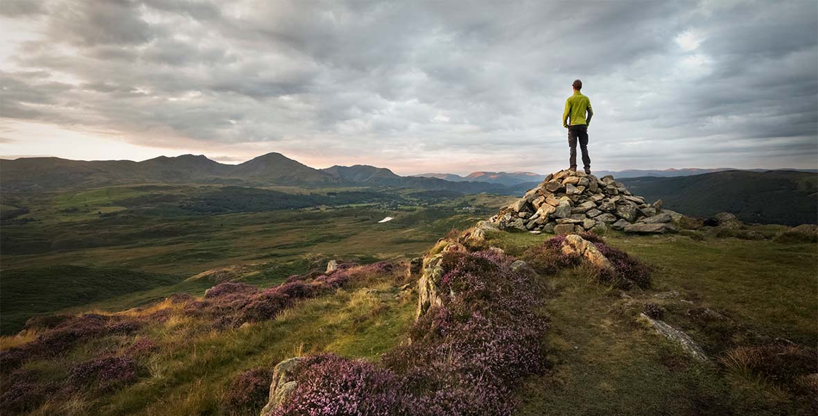 A walker admiring the view from atop a hill in the Lake District
