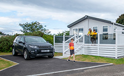 A family looking out from their lodge veranda at Nairn Lochloy Holiday Park