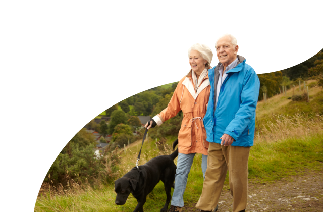 Elderly man and woman on a dog walk through the hills