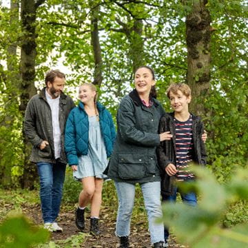Family walking arm in arm through woods