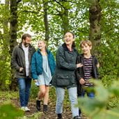 Family walking arm in arm through woods